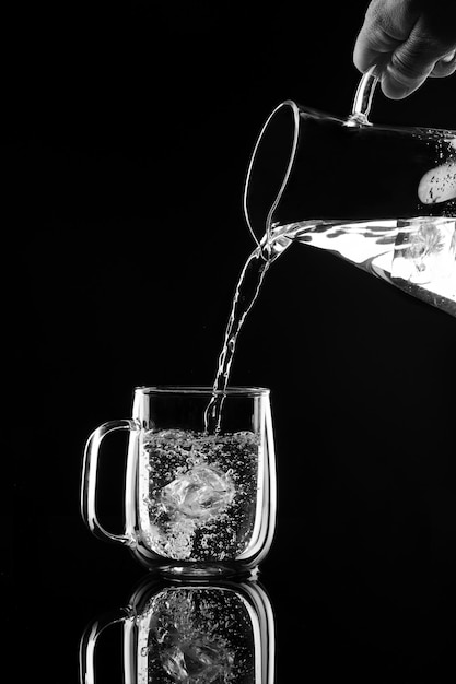 Photo water pours on a black background into a glass