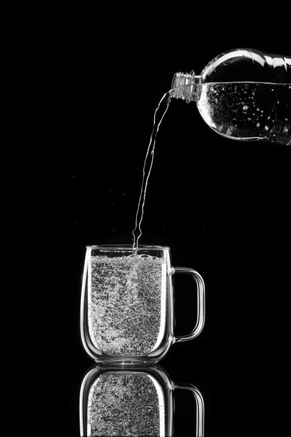 Water pours on a black background into a glass