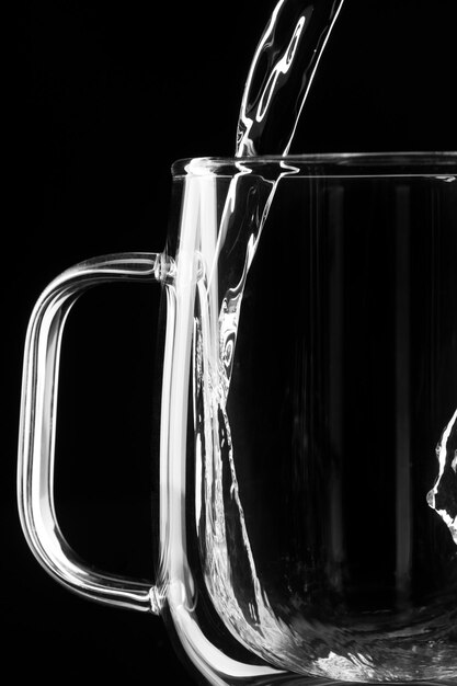 Water pours on a black background into a glass