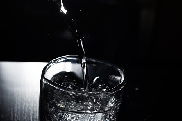 Water pours into a glass in the dark