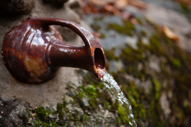 Water pours out of a stream from an old jug