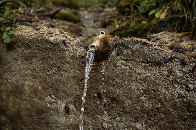 Photo water pours out of a stream from an old jug