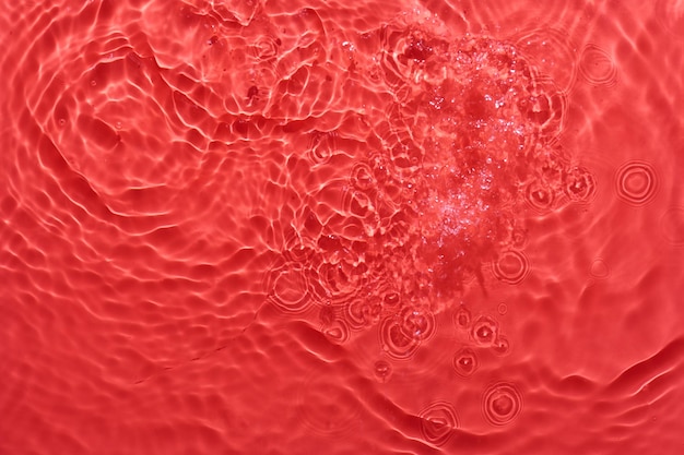 Water red surface abstract background Waves and ripples texture of cosmetic aqua moisturizer with bubbles