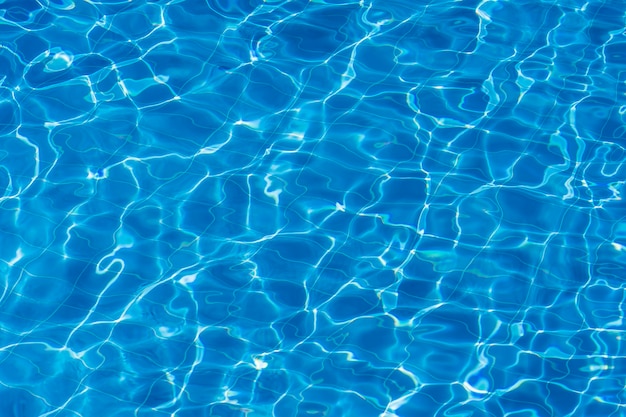 写真 青いタイル張りのスイミングプールの背景に水の波紋。ブルーターコイズのプールの水。波紋は太陽に照らされました。下に見えるタイル。上面図