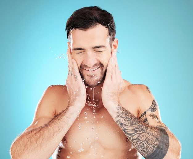 파란색 배경에 격리된 수염 아침 미용 트리트먼트를 청소하는 물 스킨케어 및 남자 얼굴 위생 스플래쉬 및 스튜디오에서 건강 웰빙 및 스파 스킨 케어를 위한 남성 모델 손질 얼굴