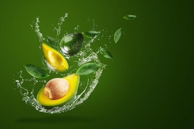 Water spatten op verse gesneden groene avocado op de groene achtergrond.