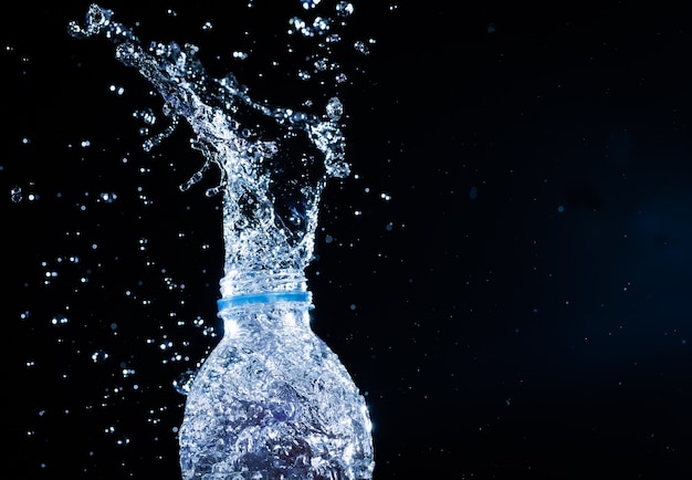 Water spatten uit de fles op zwarte achtergrond