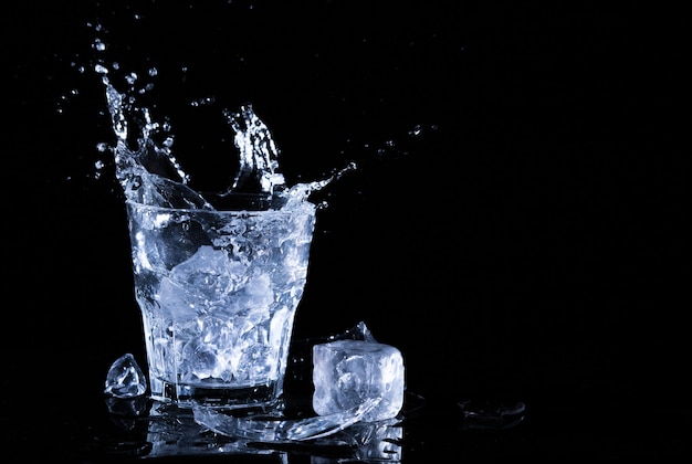 Spruzzata dell'acqua in un bicchiere. un bicchiere di acqua fredda. acqua fredda con ghiaccio