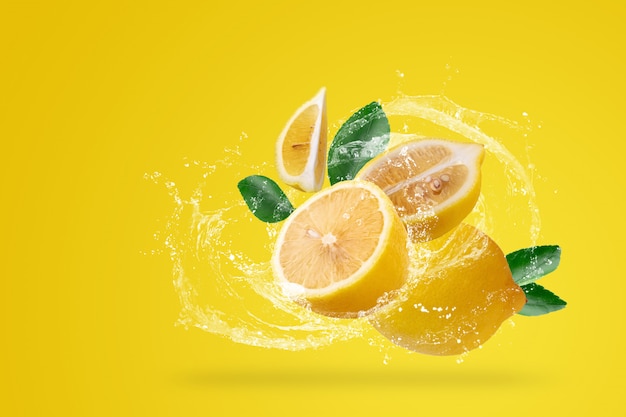 Брызги воды и желтый лимон фрукты на желтом фоне.
