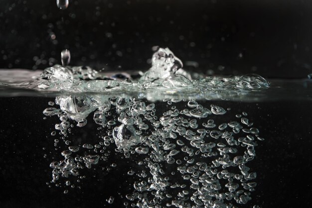 Water splashing as it\'s poured into aquarium tank, black\
background