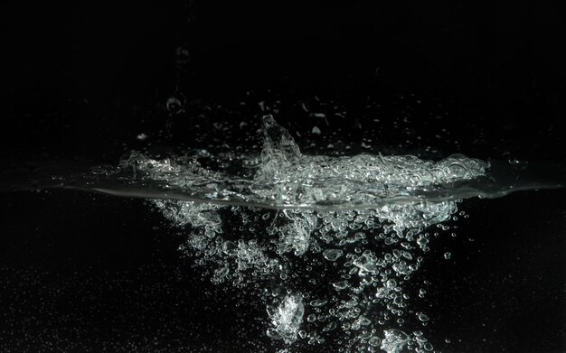 Water splashing as it's poured into aquarium tank, black background