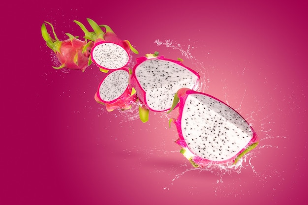 Spruzzi d'acqua su dragonfruit o pitaya isolati su uno sfondo rosso