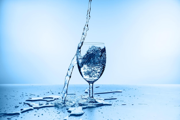 Foto spruzzi d'acqua dal vetro isolato su sfondo blu