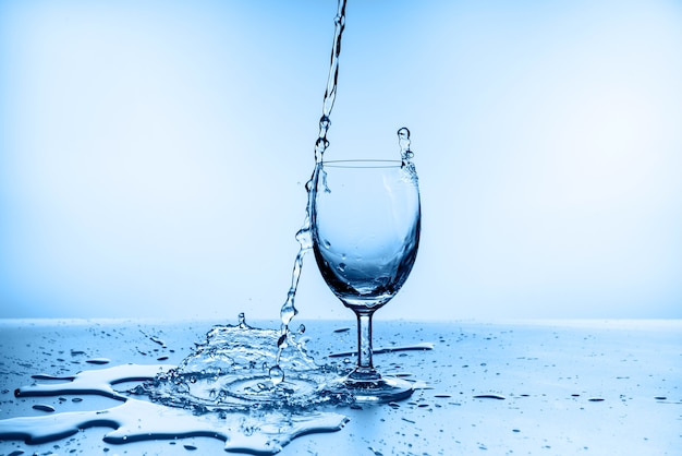 Water splashing from glass isolated on blue wall