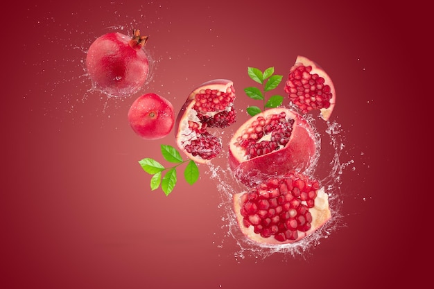 Water splashing on Ripe pomegranate fruit on red background