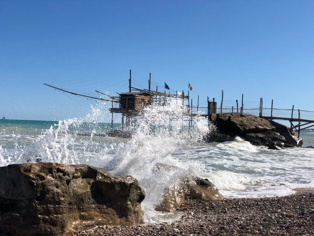 Water splashing on rocks against sky