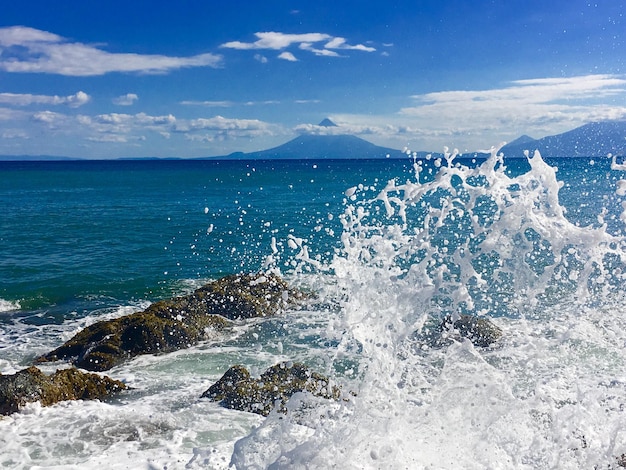 Foto l'acqua spruzza sulle rocce dal mare contro il cielo