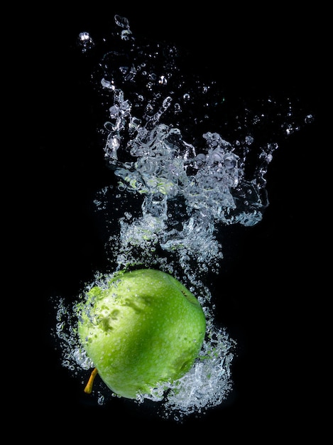 Вода брызгает с зеленым яблоком.