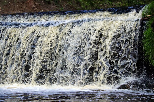 Water stream cascade falling on the rocks close up