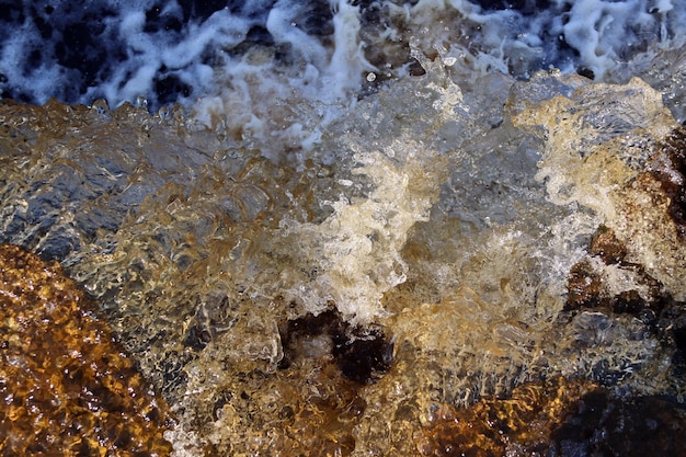 Каскад струи воды падает на скалы крупным планом