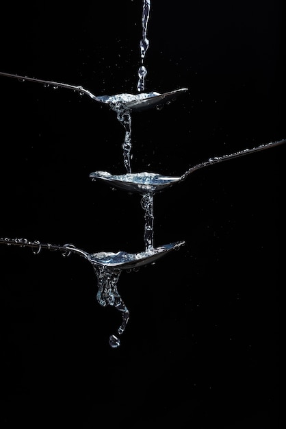 Foto water stroomde in een lepel en van daaruit naar een andere lepel.