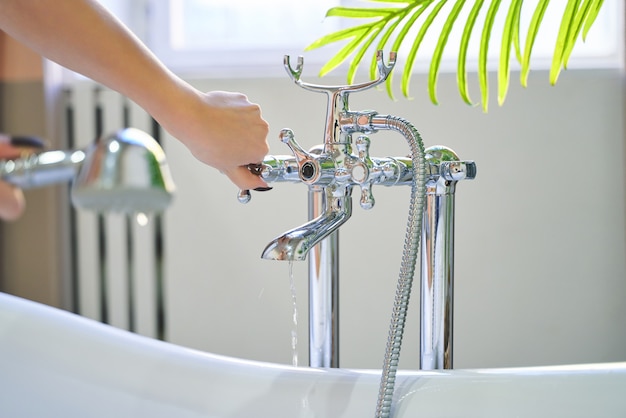 Water stroomt uit de douche op de handen van het meisje.