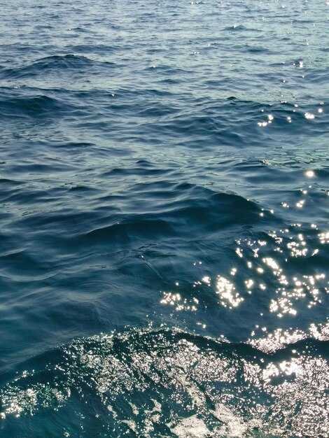 Water surface with waves and sunny rays on summer day