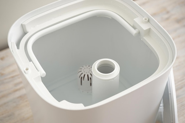 Water tank in a modern humidifier, filling the reservoir water in the room. Close-up.