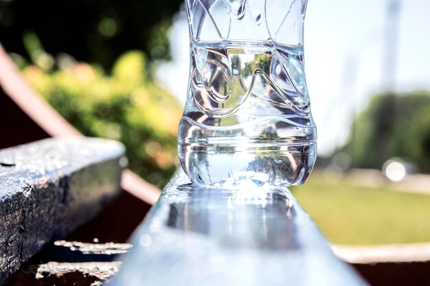 Acqua in una bottiglia trasparente su una panca di legno