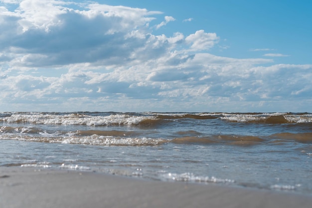 明るい青い空の地平線に対する泡と水の波と海の潮、ターコイズブルーの海または海面で砕ける波