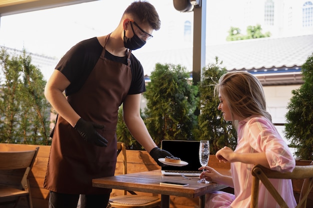 Water werkt met gezichtsmasker in restaurant, uitbraak van coronavirus