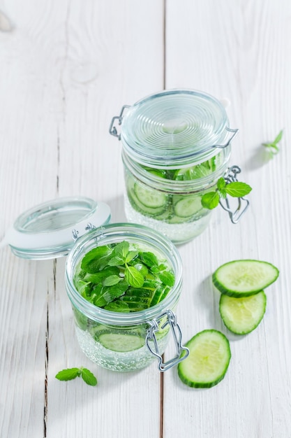 Water with fresh cucumber and mint on white table