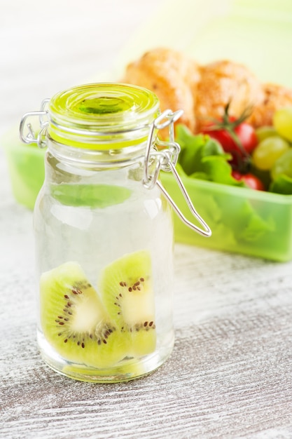 Water with kiwi and green lunch box