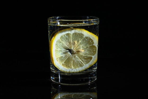 Acqua con limone su sfondo nero scuro