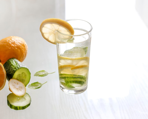 Acqua con limone e cetriolo in un bicchiere su sfondo chiaro. bevanda detox.