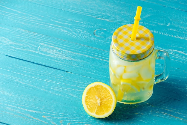 Water with lemon. Lemonade with lemon slices, jar with straw