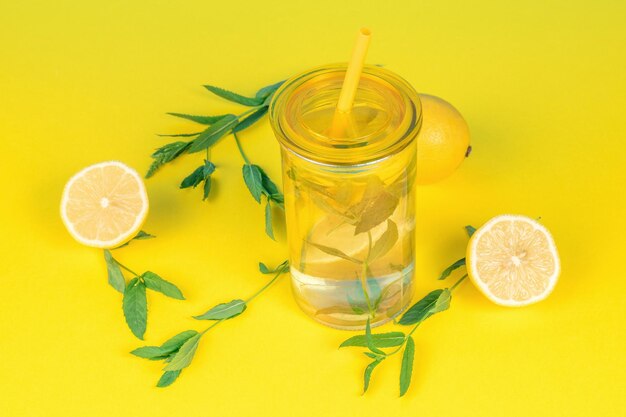 Water with lemon and mint on a bright yellow background