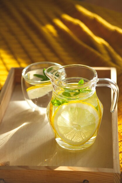 Water with lemon in a transparent bowl on a tray