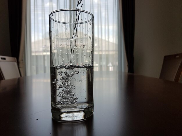 Foto water wordt in een glas op tafel gegoten thuis