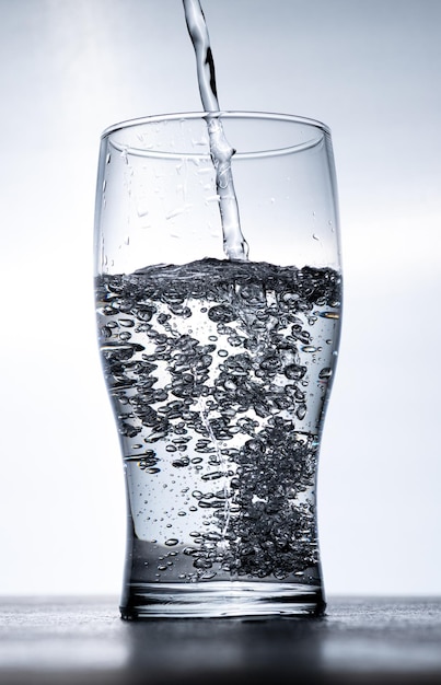 Water wordt van bovenaf in een glas gegoten