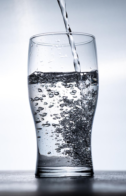 Water wordt van bovenaf in een glas gegoten