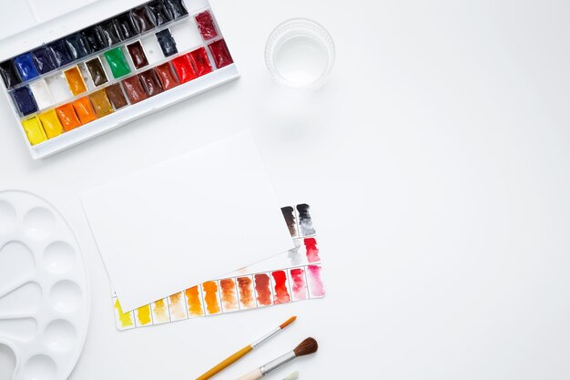 Watercolor and other artistic accessories on a white background Artist's desk workplace Top view