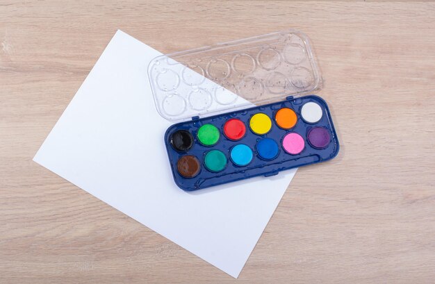 Premium Photo | Watercolor paint box on a sheet of paper a wooden