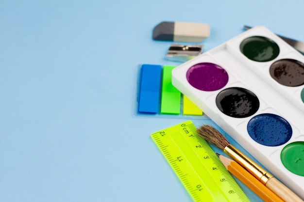 Watercolor paints lie on the stationery on a blue background.