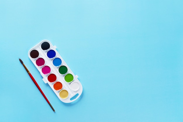 Watercolor paints with a brush on a blue background Back to school concept