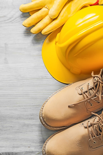 Waterdichte veterlaarzen veiligheidshelm beschermende handschoenen op houten plank bouwconcept