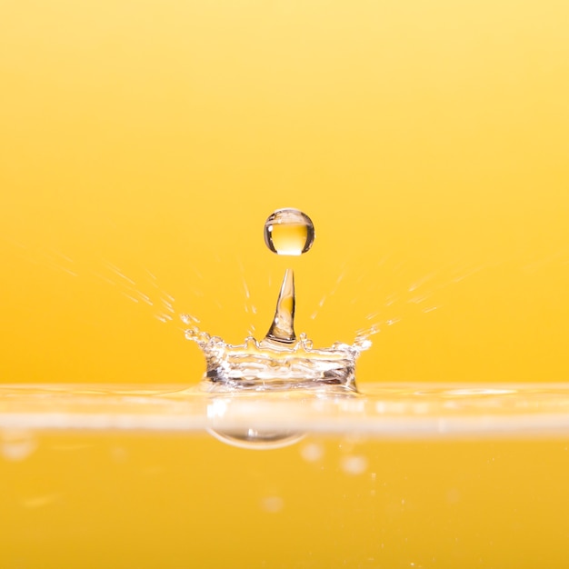 Foto waterdrop die op geel valt