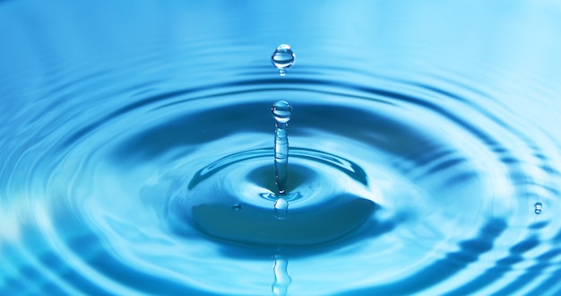 Waterdruppel vallen in water waardoor een perfecte concentrische cirkels. Abstracte blauwe achtergrond