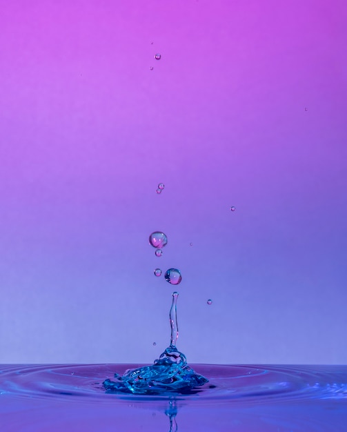 Foto waterdruppelbotsingen macrofotografie met roze en blauwe achtergrond