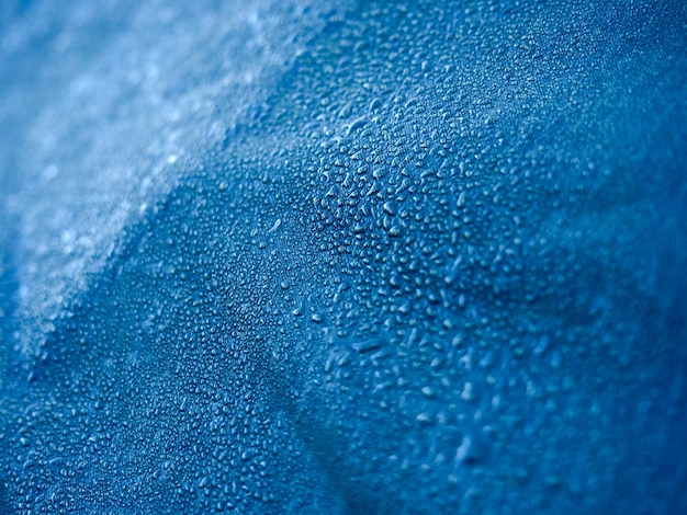 Waterdruppels op waterdichte membraanstof. Detailweergave van textuur van blauwe synthetische waterdichte doek. Ochtenddauw op tent.